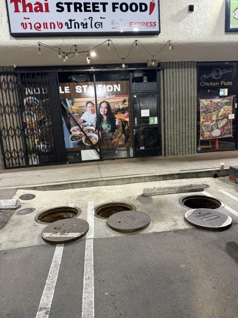 Open underground grease trap with lid removed during routine commercial grease trap service and inspection