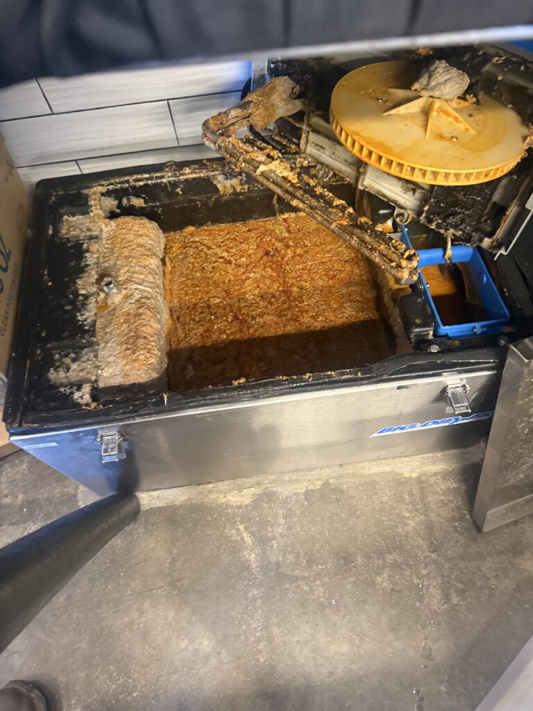 Overflowing grease trap during grease trap maintenance operation at a commercial kitchen.