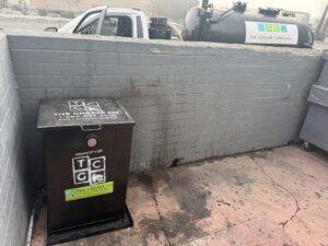 Commercial grease trap outside a restaurant showing DIY grease trap cleaning procedure guidance by The Grease Company.