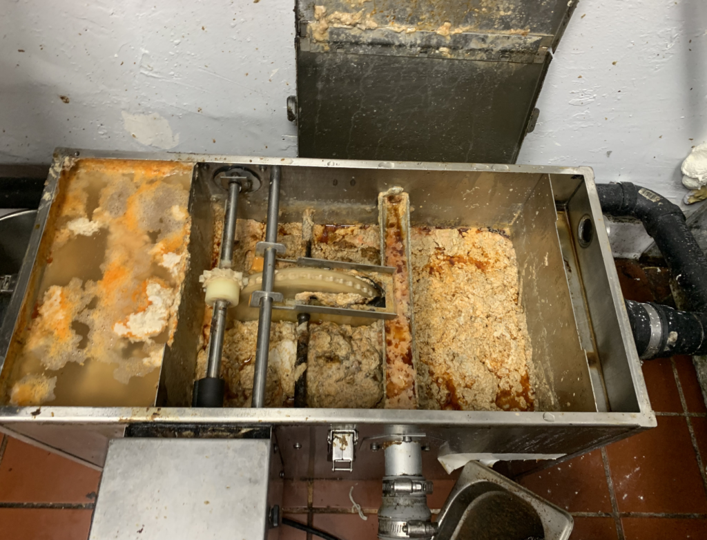 Full and overflowing grease trap in Southern California food production facility requiring emergency grease trap cleaning service