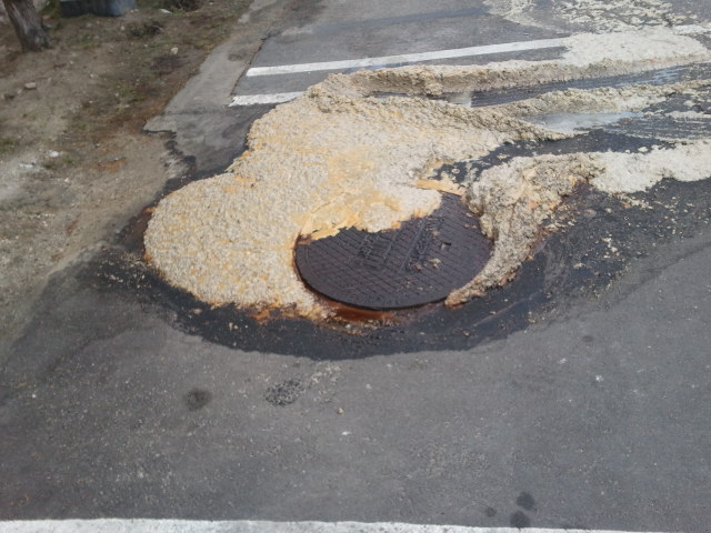 Overflowing grease interceptor causing grease trap odor, sewage-like smell, and wastewater backup in a commercial kitchen drainage system.