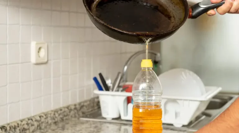 Commercial kitchen staff pouring used food grade cooking oil for recycling