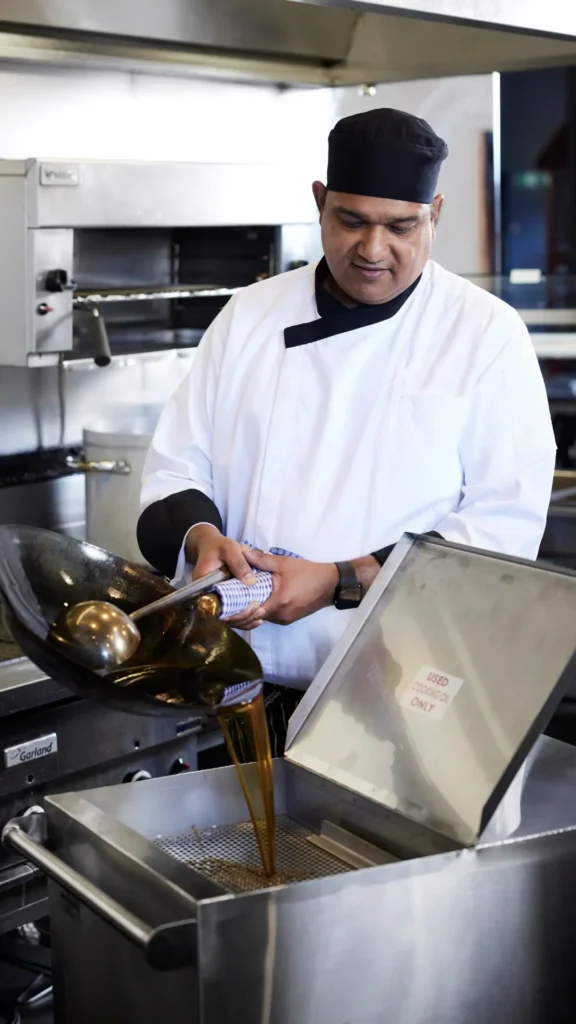 Kitchen staff filtering used oil before used fryer oil disposal